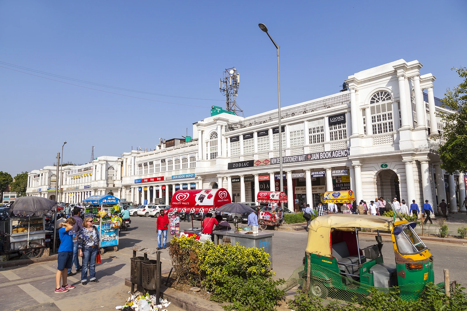 Auto-rickshaws and shoppers outside the white colonnades of Connaught Place, New Delhi