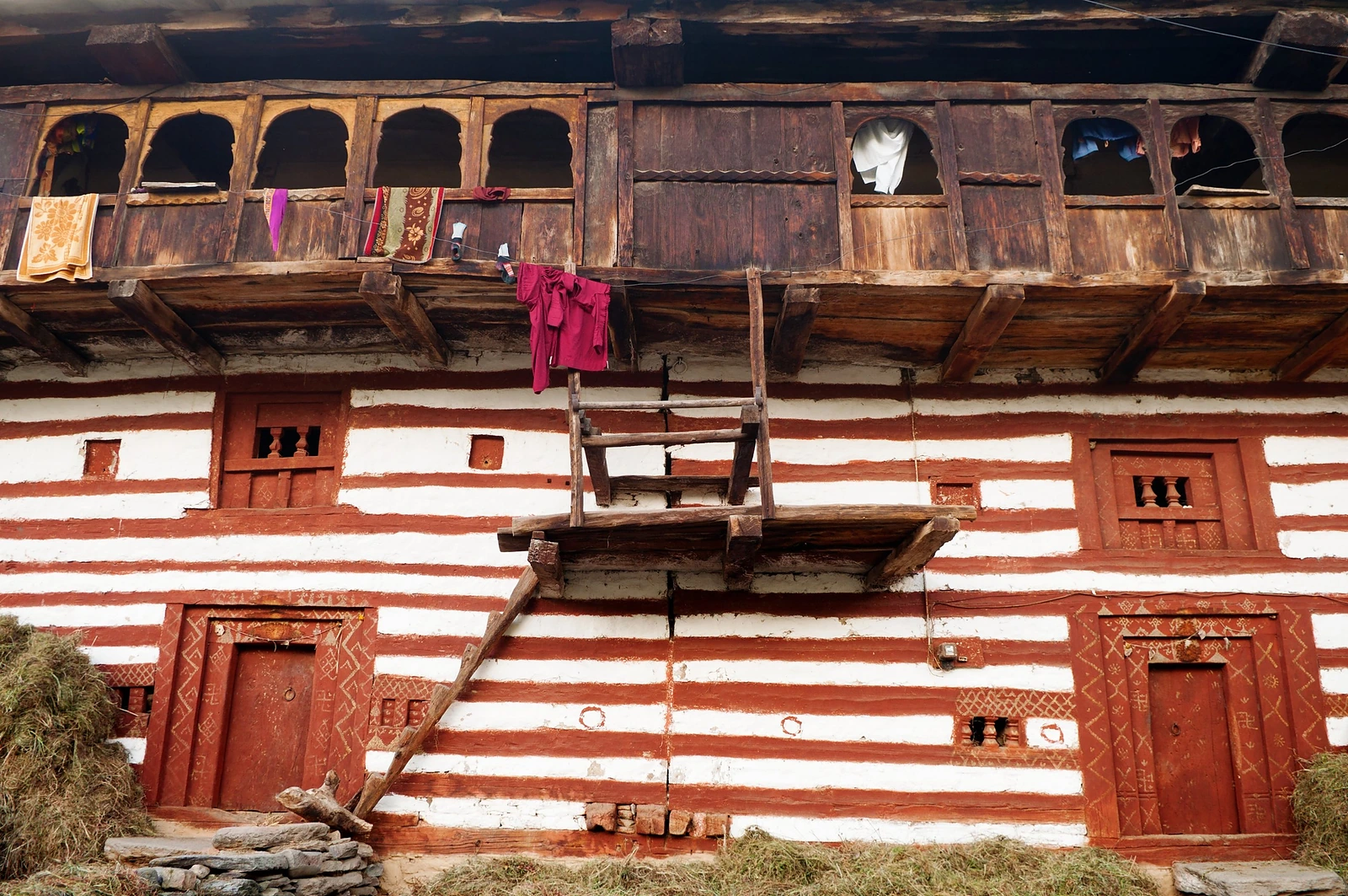 A traditional house of timber and whitewashed stone with a carved wooden balcony
