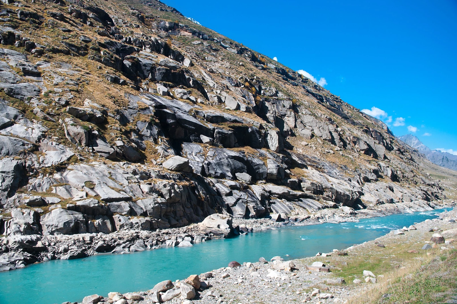 Une rivière turquoise au pied d’une montagne rocheuse escarpée