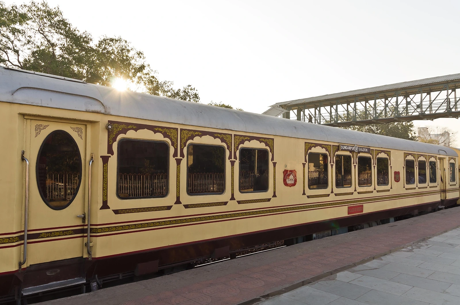 The cream and maroon Dungarpur Saloon carriage of the Palace on Wheels at a station platform, in the late sun