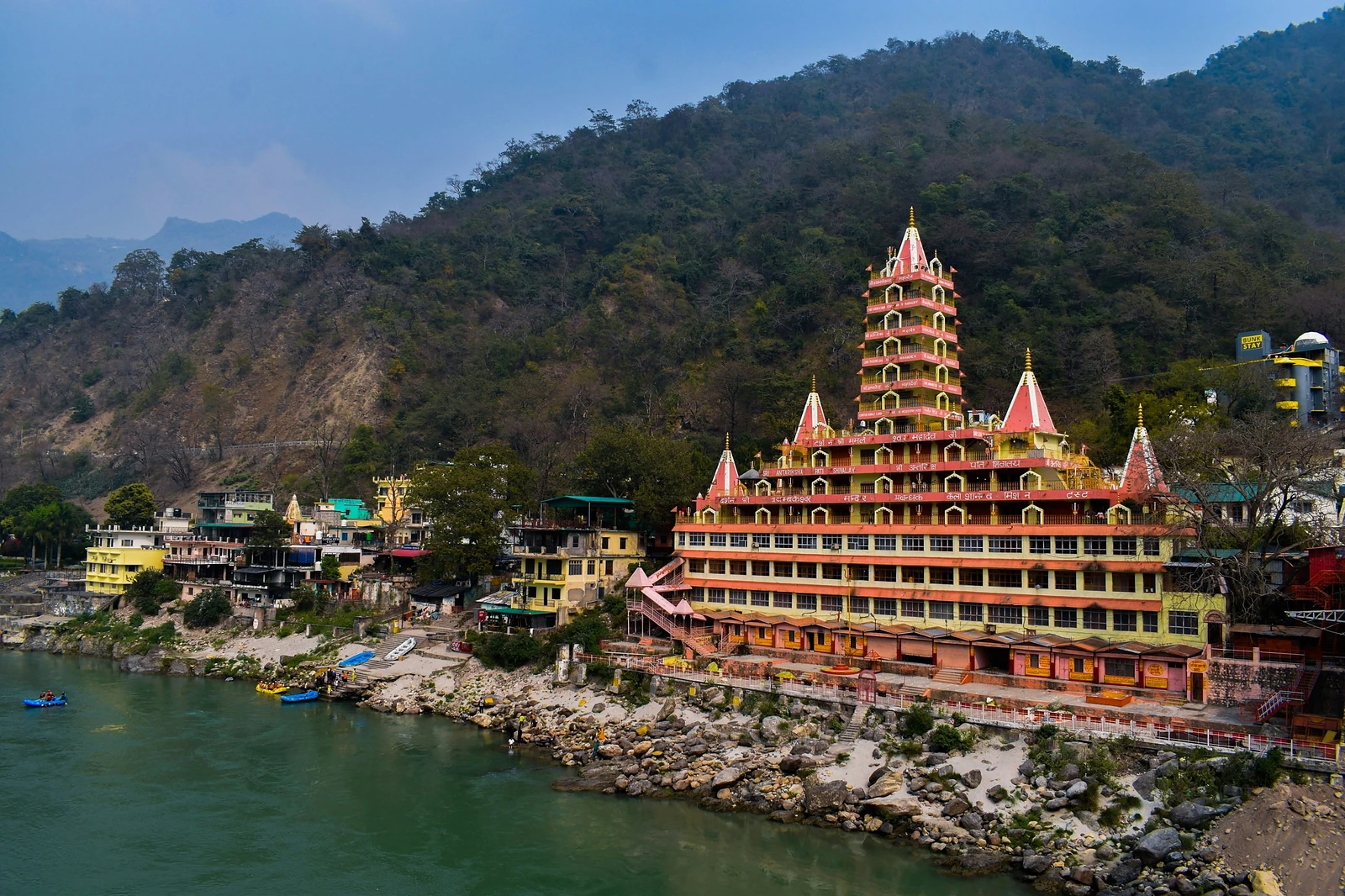 The many-storeyed Trimbakeshwar temple above the Ganges at Rishikesh, with forested hills behind