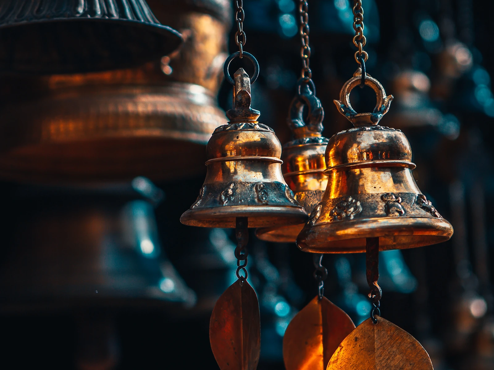 Brass bell hanging against a carved wooden wall in Bhaktapur